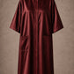 Burgundy iridescent snap-front salon robe front view with black collar trim, short sleeves and front pockets