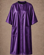 Purple iridescent snap-front salon robe front view with black collar trim, short sleeves and front pockets