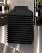 Baker’s Dozen stack of 13 black SalonCapes waterproof chemical aprons for bulk salon ordering