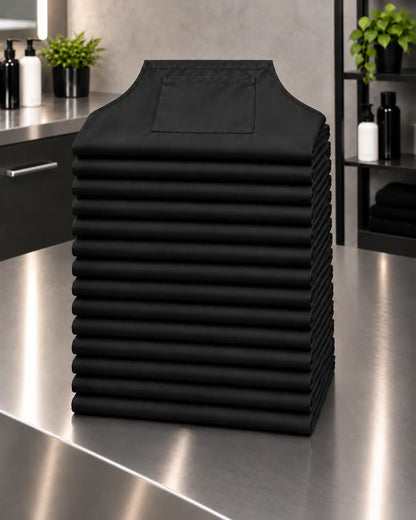 Baker’s Dozen stack of 13 black SalonCapes waterproof chemical aprons for bulk salon ordering