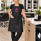 Stylist wearing a black SalonCapes waterproof chemical apron with custom embroidery and three front waist pockets in a modern salon.
