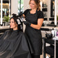 Stylist wearing a black waterproof chemical apron while applying foil highlights to a salon client