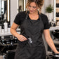 Stylist wiping white salon lightener from a black waterproof chemical apron with water beading on the fabric