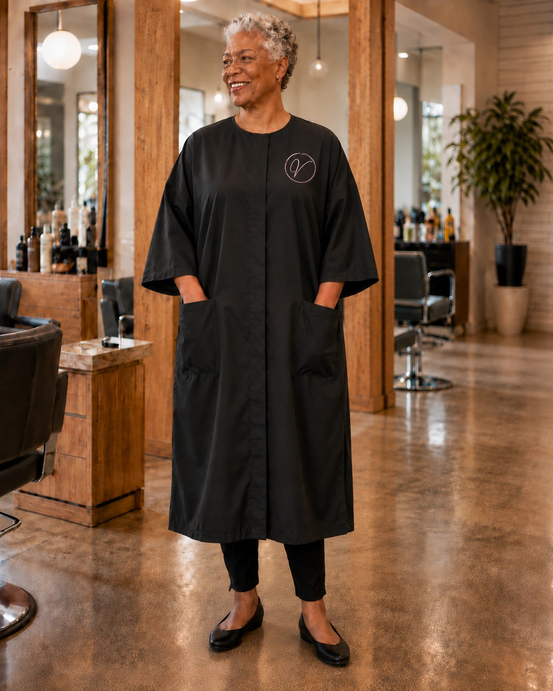 Black SalonCapes snap-front robe embroidered with Vogue Salon logo in a professional salon