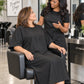Black crepe zipper-front salon robe worn during seated stylist consultation