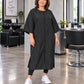 Black crepe zipper-front salon robe on woman standing in modern salon