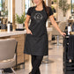 Black iridescent SalonCapes apron with custom white Apothecary Salon embroidery centered on the chest