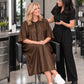 Iridescent brown zipper-front salon robe worn during seated stylist consultation