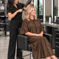 Iridescent brown zipper-front salon robe worn during professional blow-dry service