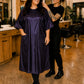 Woman wearing an eggplant iridescent snap-front salon robe with short sleeves and front pockets in a professional salon