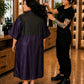 Eggplant iridescent snap-front salon robe with black waterproof back panel and water droplets during salon use