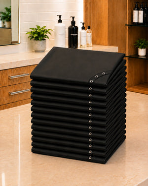Stack of 13 black SalonCapes chemical capes representing the Baker’s Dozen bulk purchase option