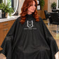Black SalonCapes cutting cape embroidered with Union Street Salon logo on seated salon client
