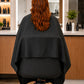 Black SalonCapes crepe cutting cape wrapping around salon chair for extended client coverage