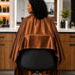 Rear view of copper iridescent SalonCapes cutting cape showing full salon-chair coverage
