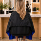 Back view of royal blue and black SalonCapes reversible chemical cape showing protective coverage and seam construction